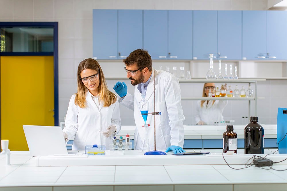 Researchers working with blue liquid at separatory funnel in the laboratory